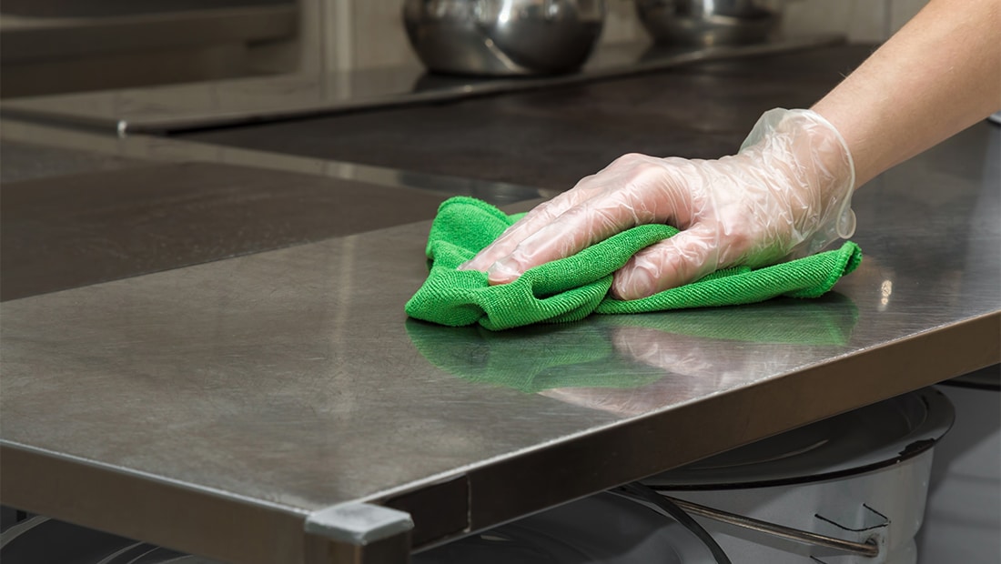 A Country Hearth sanitation worker wipes down the countertop of a baking operating to ensure that the surfaces are food safe.